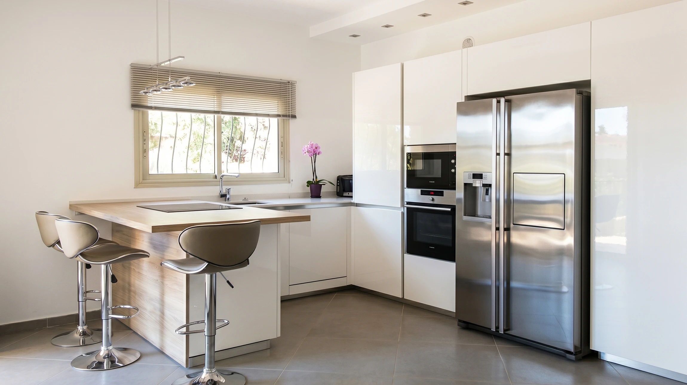 Photographie d'une cuisine aménagée haut de gamme entièrement conçue et fabriquée par un artisan menuisier, montrant un espace cuisine moderne et élégant avec meubles sur mesure, plan de travail en matériaux nobles, éclairage intégré, photographiée dans un intérieur lumineux et professionnellement composée.